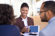 © Mangostar - Joyful successful sales agent presenting content on tablet to clients. African American business woman speaking, smiling and showing blank tablet screen to colleagues or partners. Negotiation concept