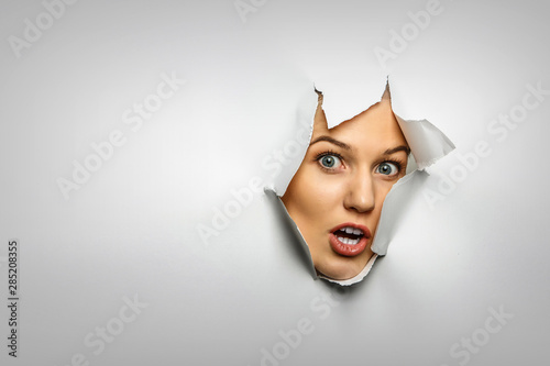 Fotomural Woman looking out from a hole of torn paper
