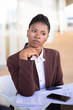 © Mangostar - Pensive young businesswoman thinking over contract terms. Serious African American business woman sitting at table with documents. Paperwork concept