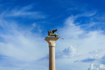 Wall Mural - Saint Mark Winged Lion medieval statue, a symbol of the Old Venice Republic, at the top of an ancient column among clouds