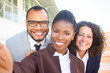 © Mangostar - Happy black businesswoman taking group selfie with team. Self portrait of successful multiethnic business man and women. Collective selfie concept