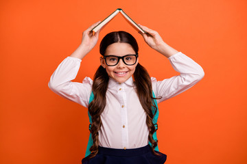 Poster - Portrait of lovely sweet school people hold hand printed book eyewear eyeglasses positive backpack bag rucksack cheerful trendy white skirt dress blouse naughty isolated orange background