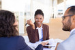 © Mangostar - Happy African American business woman discussing deal with partners. Multiethnic business partners sitting at table with documents in outdoor cafe and talking. Partnership concept