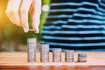 Hand holding coin and Coins stack on wood table money business finance concept