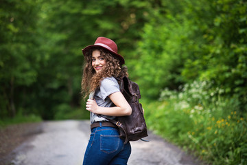 Wall Mural - young tourist woman traveller with backpack walking in nature.
