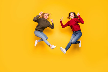 Poster - Full length photo of cute ladies jumping high showing v-signs wear knitted pullovers isolated yellow background