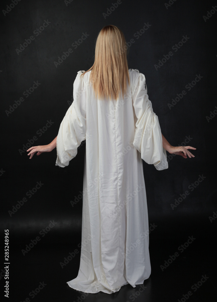 full length portrait of blonde girl wearing long white flowing robe ...