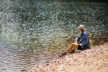 Tourist young man walking on the forest lake beach in summer. Vacation concept