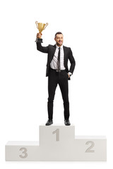 Wall Mural - Man in a suit posing on a pedestal with a golden trophy cup on first place