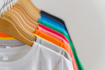 close up of colorful t-shirts on hangers, apparel background