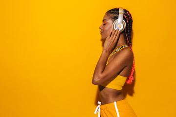 Wall Mural - Image of pretty african american woman wearing afro braids listening to music with headphones