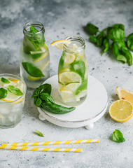 Summer basil lemonade on grey background. Fresh summer cocktail with basil, lemon and ice cubes. Homemade fresh lemonade with lemon and basil. Food and drink concept