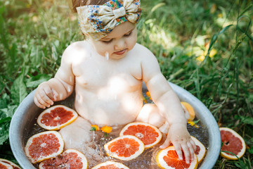 Wall Mural - Baby taking a fruit bath outside in a basin 