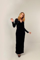 Wall Mural - full length portrait of blonde woman wearing long  lace gown, standing pose against a creamy studio background.