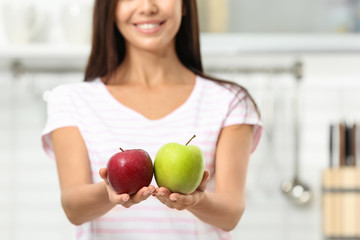 Sticker - Woman holding fresh apples in kitchen, closeup