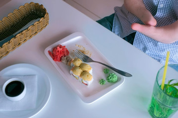 Wall Mural - Problem of adaptation to usual life guy without wrists. Disabled man with two amputated stump hands eats sushi rolls in cafe with fork, hands closeup. Independent Invalid person with disabilities.