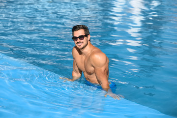 Wall Mural - Handsome young man in swimming pool on sunny day