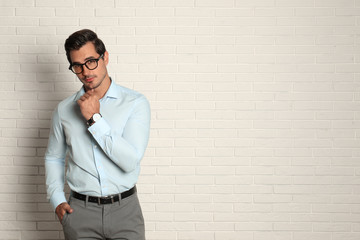 Wall Mural - Young man with glasses near brick wall. Space for text