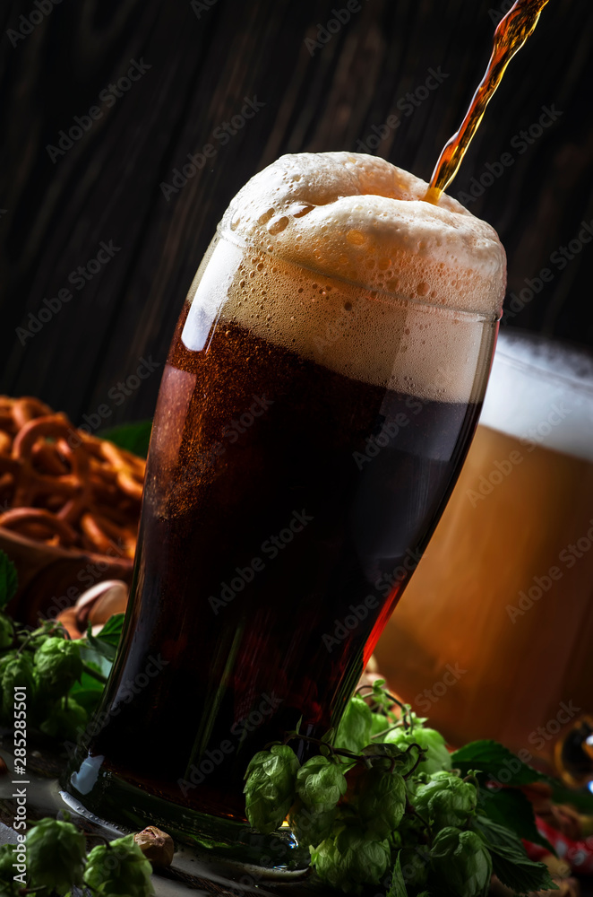 Dark english beer, ale or stout is poured into glass, dark bar counter, space for text, selective focus - obrazy, fototapety, plakaty 