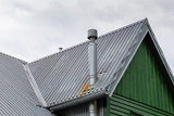 Fototapeta  - Steel roof of the old house with gutter and ventilation chimneys.