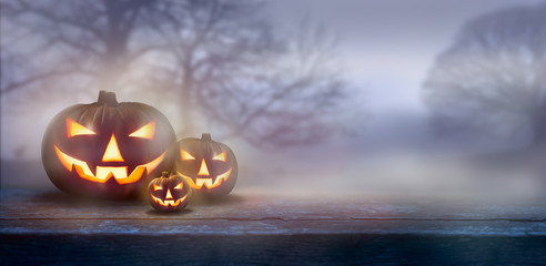 Wall Mural - a ghostly dusk in the countryside with spooky jack o' lanterns in the fog with bare trees in the bac