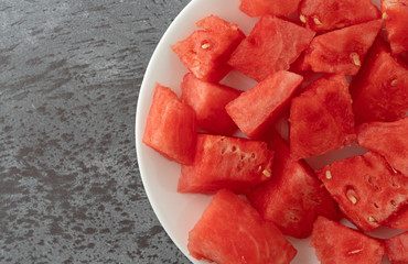 Plate of watermelon chunks on a gray mottled table top close view