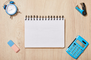 Poster - top view of empty notebook near rubber, clock and calculator on wooden desk