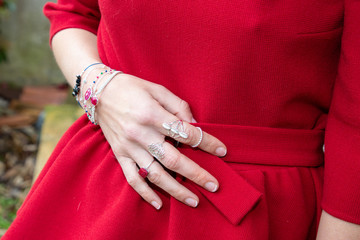 Wall Mural - Female hand with jewelry on red color dress background