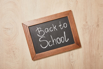 Wall Mural - top view of chalkboard with back to school lettering on wooden desk
