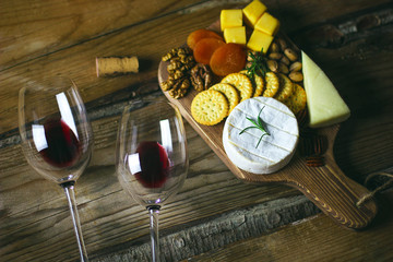 Wall Mural - two red wine glass and cheese platter on rustic background top view