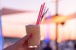 © 24K-Production - Woman's hand holding a cocktail glass against the setting sunset with blurry background