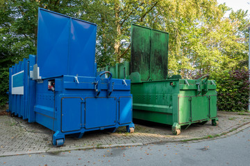 two garbage compactors standing next to each other on the premises of a hospital