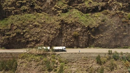 Wall Mural - flying along petrol truck driving over narrow mountain road, heavy industry and transportation in de