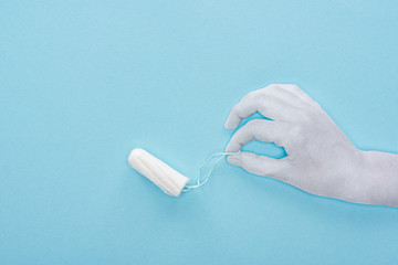 Wall Mural - top view of white paper cut hand holding cotton tampon on blue background