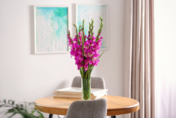 Canvas Print - Vase with beautiful pink gladiolus flowers on wooden table in room, space for text