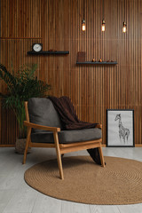 Sticker - Stylish room interior with comfortable armchair and plant near wooden wall