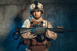 Fototapeta  - Young man in military outfit a mercenary soldier in modern times on a dark background in studio