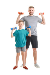 Poster - Portrait of father and son training with dumbbells on white background