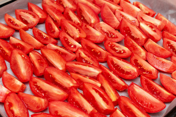 Homemade dried red  tomatoes slices with basil oregano spices cooking process. Traditional Italian Mediterranean kitchen cuisine.