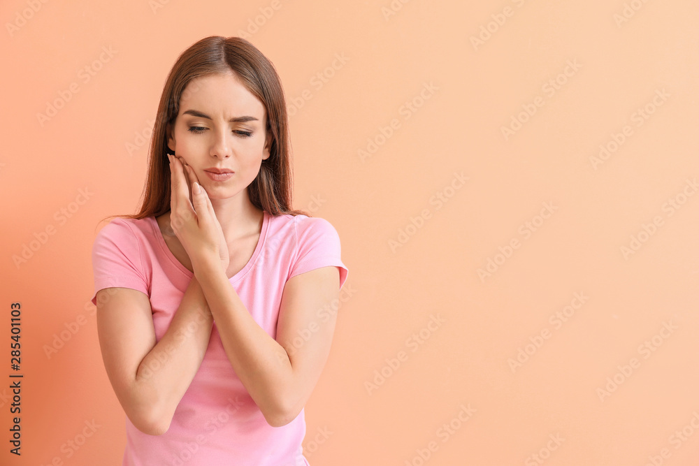 Young woman suffering from toothache against color background