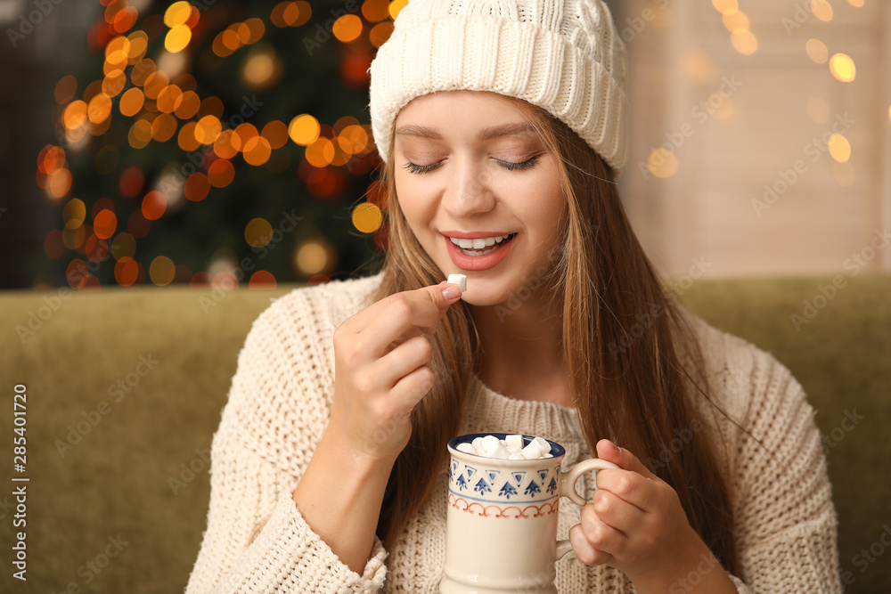Beautiful woman drinking hot chocolate with marshmallows at home