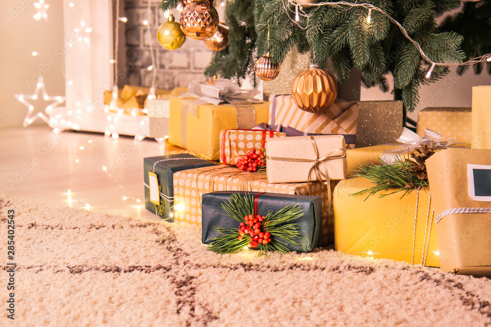 Many gift boxes under Christmas tree in room