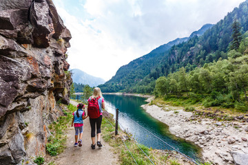 Hikers with backpack looking at mountains, alpine view, mother with child