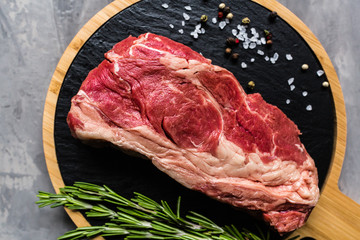 Raw meat beef on a cutting board with rosemary and spices. Top view, flat lay, mockup, copy space. Food concept