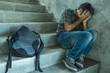 © TheVisualsYouNeed - Campaign vs homophobia with young sad and depressed college student man sitting on staircase desperate victim of harassment suffering bullying and abuse