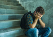 © TheVisualsYouNeed - Campaign vs homophobia with young sad and depressed college student man sitting on staircase desperate victim of harassment suffering bullying and abuse
