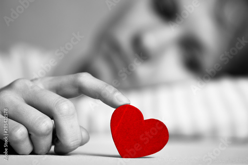Cuadros en Lienzo Sad and upset girl is touching red heart with finger