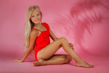 Cute Little Baby Girl In A Red Swimsuit Posing On A Pink Background. Summer Time