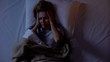 © motortion - Woman having terrible headache lying in bed at night, strong migraine, top-view