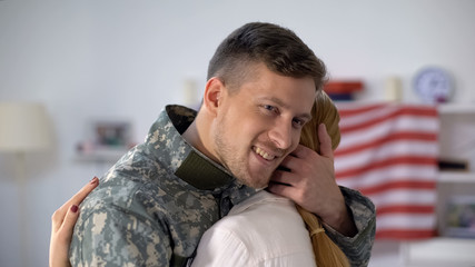 Wall Mural - Happy US soldier embracing wife with love, homecoming after military service